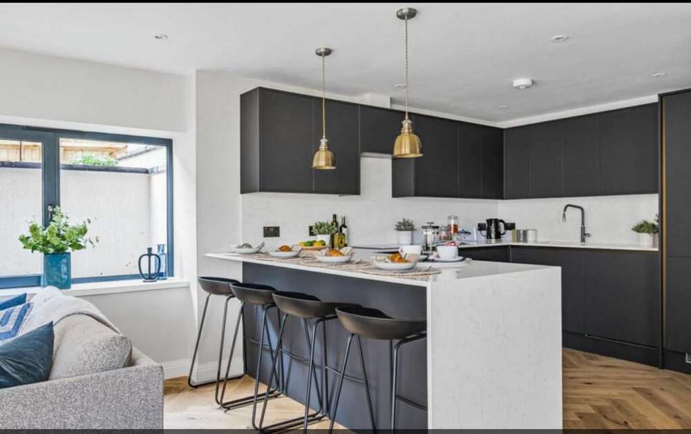 https://usedkitchenhub.com/wp-content/uploads/2023/12/Howdens-Hockley-Charcoal-Super-Matt-Handleless-Kitchen-Peninsular-%E2%80%93-Neff-Bosch-Appliances-Quartz-Worktops-inc-Waterfall-Side-00003.jpg