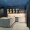 Ex Display Italian Luxury Ernestomeda One Fenix Bianco Kos Glass In Fume Rovere Blackwood Pocket Door Kitchen including Peninsular with Wooden Breakfast Bar – Bora Siemens Appliances - Stone Italiana Marmorea Golden Worktops