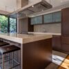 Luxury Polyform Walnut Kitchen with Pocket Doors and Matching Island - Gaggenau Verenna & Foster Appliance – Sand Coloured Corian Worktops