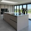 Young Modern Slab Wren Cashmere Kitchen with Large Matching Island – AEG Appliances – Quartz Worktop
