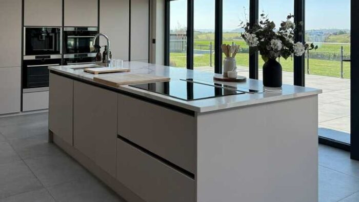 Young Modern Slab Wren Cashmere Kitchen with Large Matching Island – AEG Appliances – Quartz Worktop